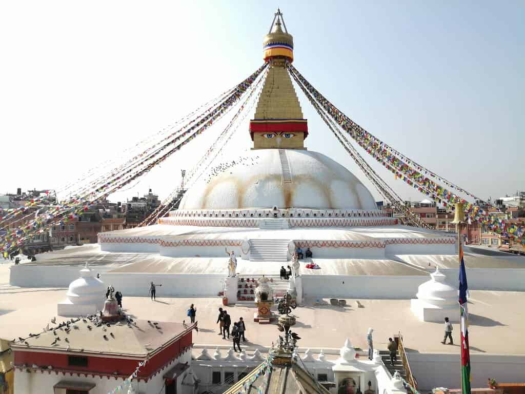 Spherical Boudhanath with white walls and decorative flags strained from spire located in Kathmandu Nepal